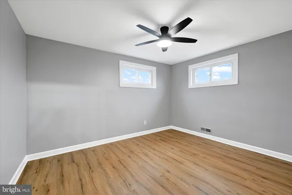 a view of a big room with wooden floor and windows