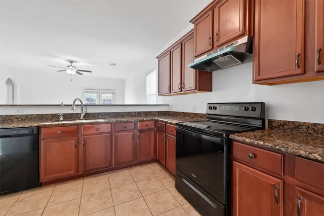 a kitchen with granite countertop a stove top oven microwave and cabinets