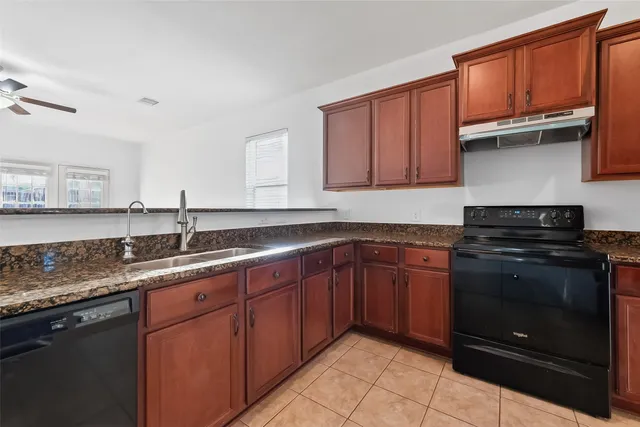a kitchen with granite countertop a sink stove and refrigerator