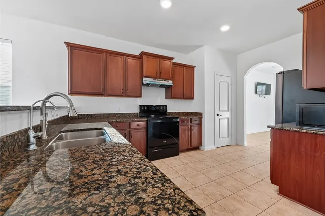 a kitchen with stainless steel appliances granite countertop a sink refrigerator and cabinets