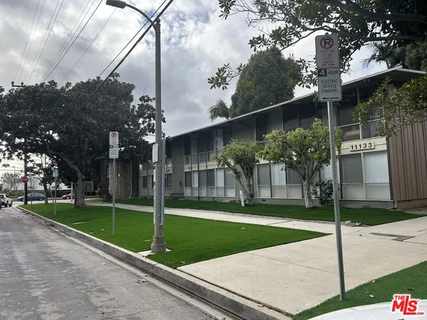 a view of a white house with a big yard and a large tree