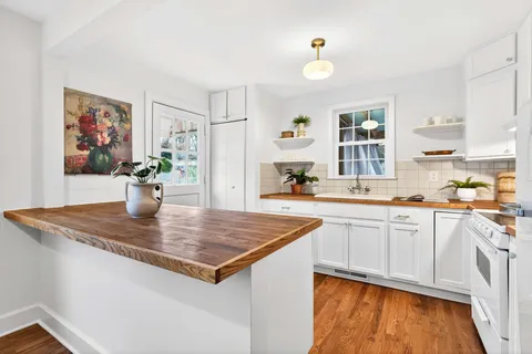 a view of kitchen island a sink wooden floor dining table and chairs