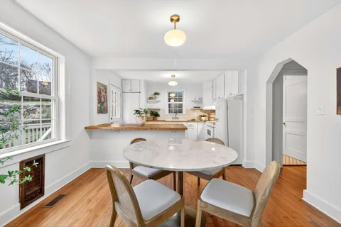 a kitchen with stainless steel appliances granite countertop a dining table chairs and a refrigerator a sink with wooden floor