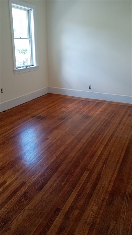 89 Franklin Street, Unit 89 Boston, MA 02134 - Photo 12 of 17 an empty room with wooden floor and windows