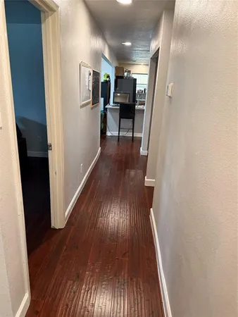 a view of a hallway with wooden floor and furniture