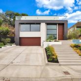 a front view of a house with a yard and potted plants
