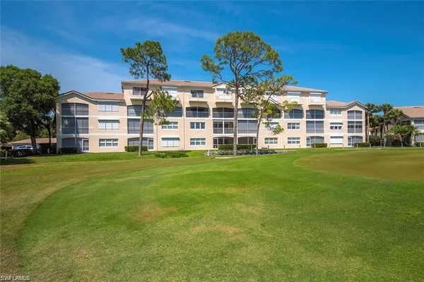 a view of a building with a big yard and large trees