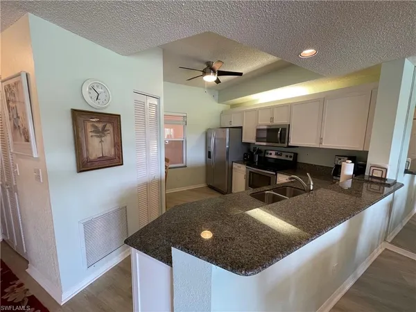a kitchen with stainless steel appliances granite countertop a sink a refrigerator and a granite counter tops