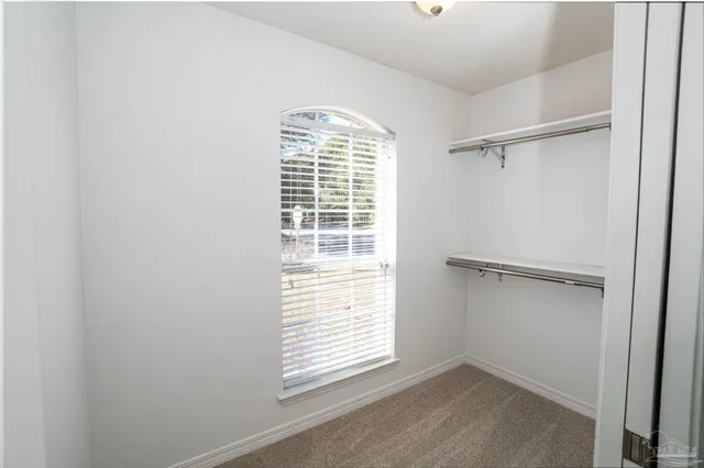 a view of an empty room with a window and closet area