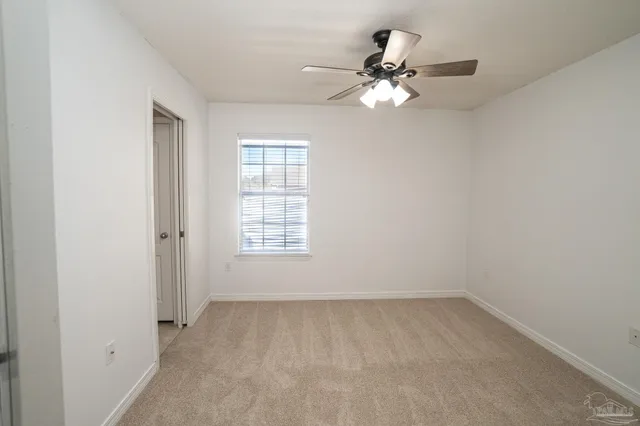 an empty room with a chandelier fan and windows