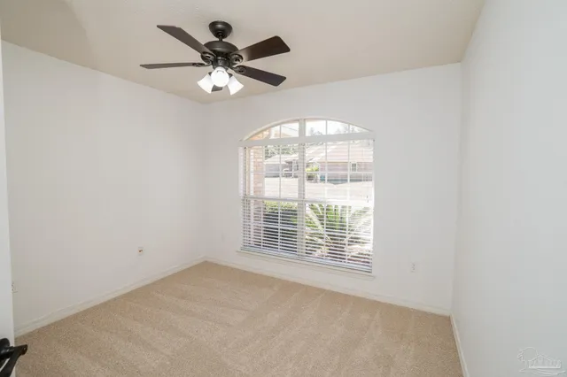 an empty room with windows and ceiling fan