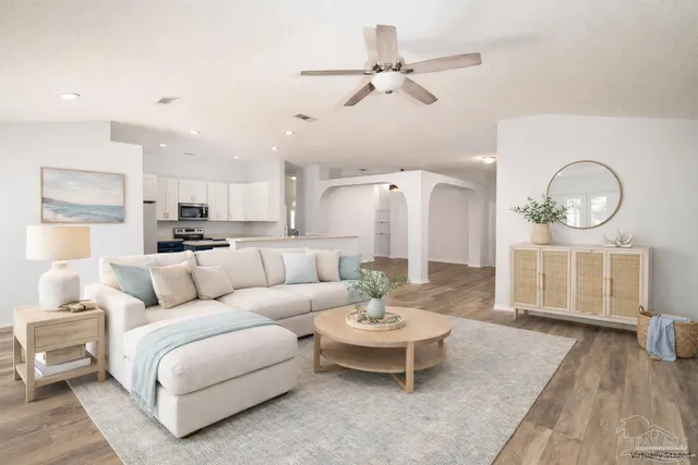 a living room with furniture kitchen view and a wooden floor