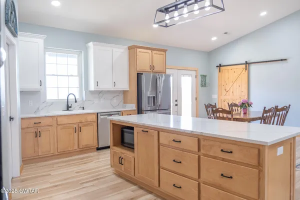 a kitchen with stainless steel appliances granite countertop a refrigerator a stove a sink and white cabinets with wooden floor