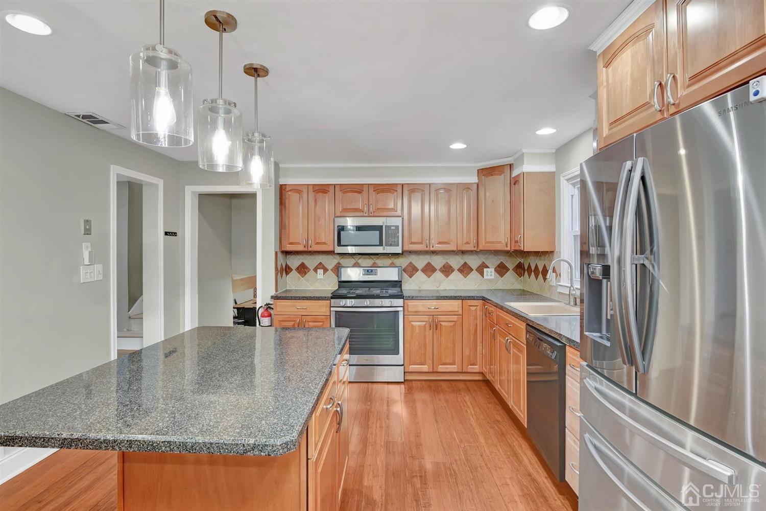 423 Ridge Road Dayton, NJ 08810 - Photo 14 of 29 a kitchen with stainless steel appliances granite countertop a refrigerator a sink dishwasher a stove and white cabinets with wooden floor