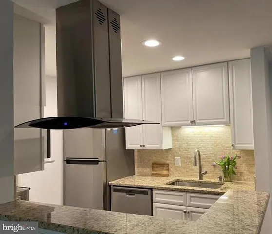 a kitchen with stainless steel appliances granite countertop a refrigerator a stove and a sink