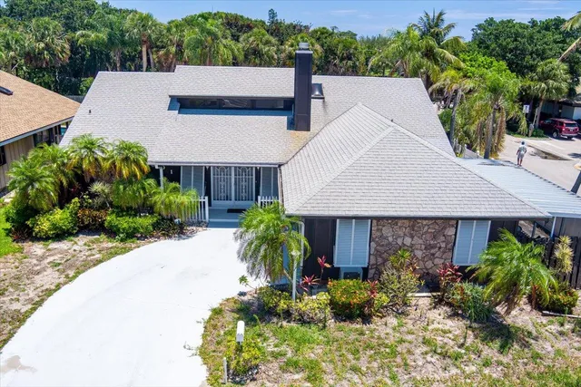 a palm tree sitting in front of a house with a yard