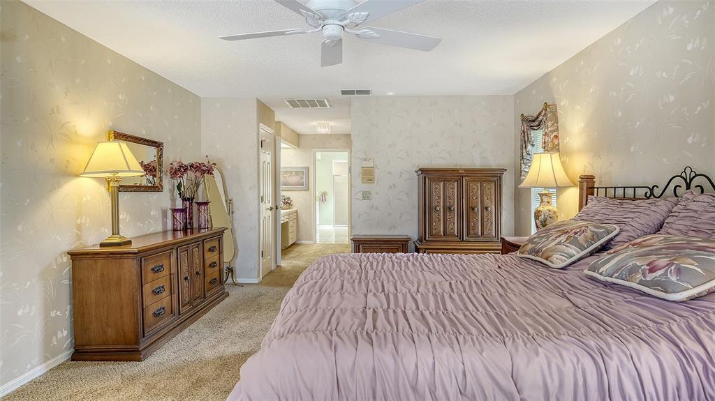 7426 Weeping Willow Boulevard Sarasota, FL 34241 - Photo 30 of 66 a spacious bedroom with a bed and a chandelier