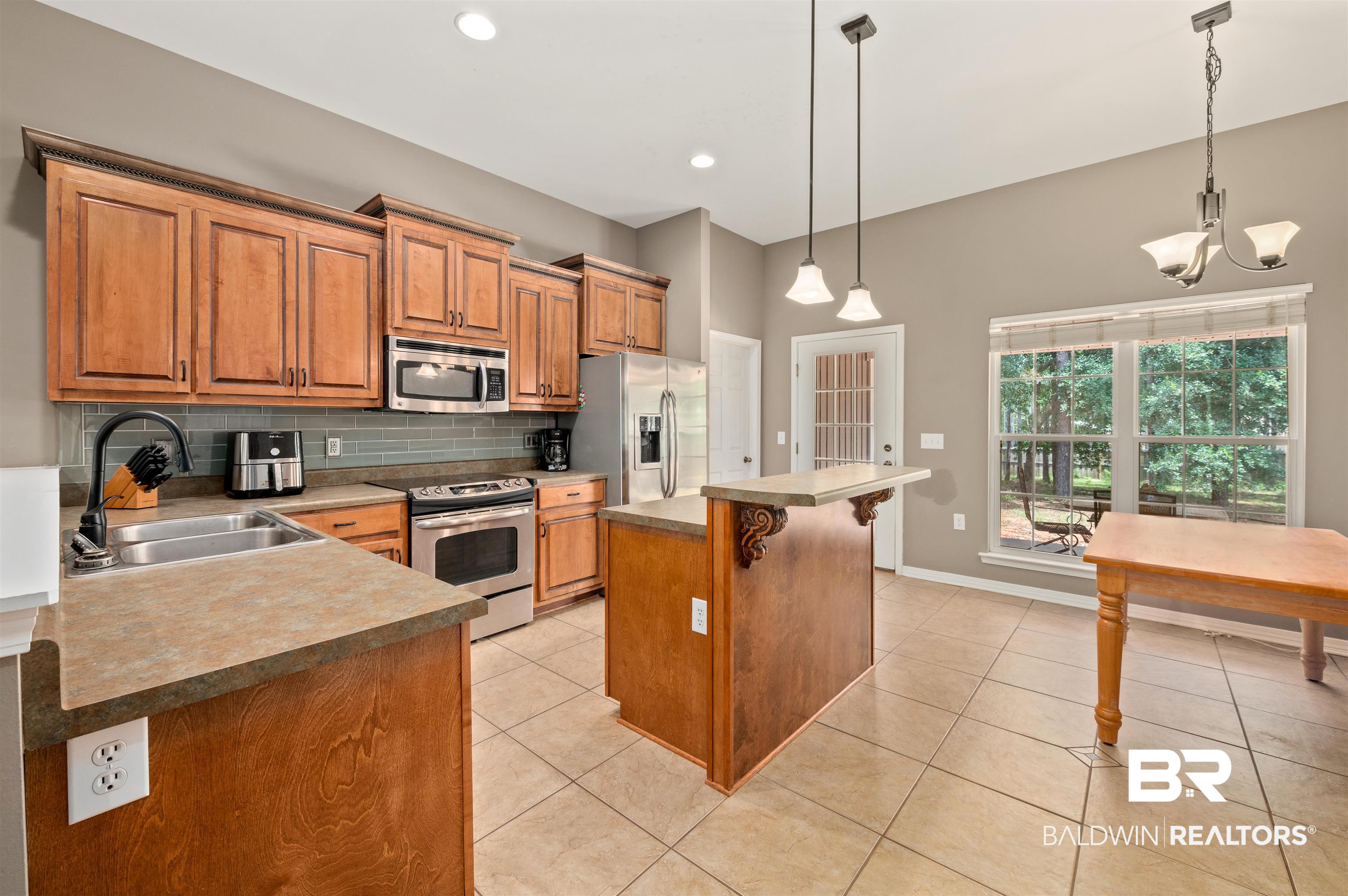 15240 Styx River Road Stapleton, AL 36578 - Photo 16 of 18 Kitchen featuring decorative light fixtures, stainless steel appliances, sink, and a center island