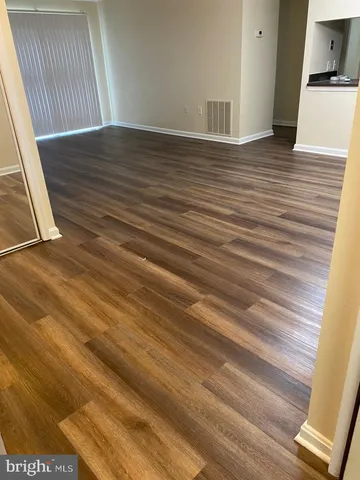 a view of an empty room with wooden floor and a cabinet