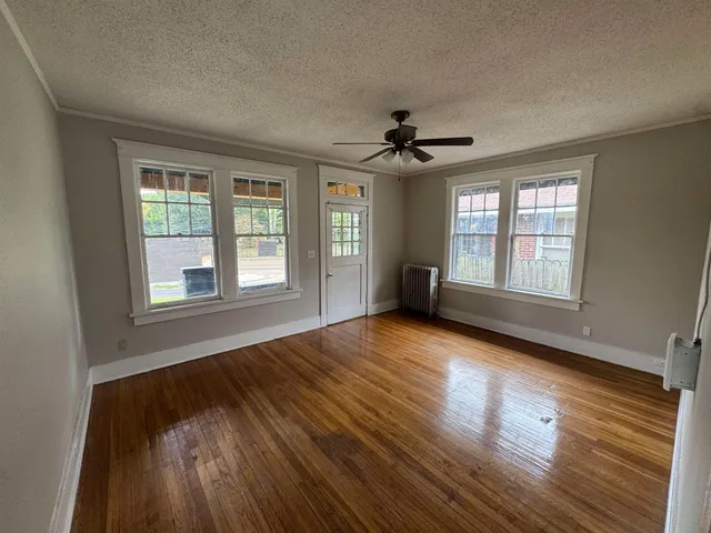 a view of an empty room with wooden floor and a window