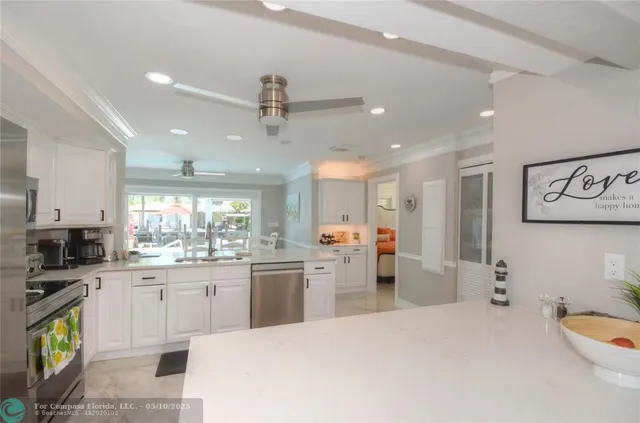 a large white kitchen with a refrigerator a sink dishwasher a dining table and chairs