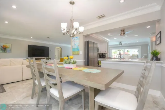 a view of a dining room with furniture a chandelier and kitchen view