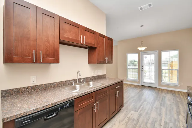 a kitchen with granite countertop wooden cabinets a sink and dishwasher