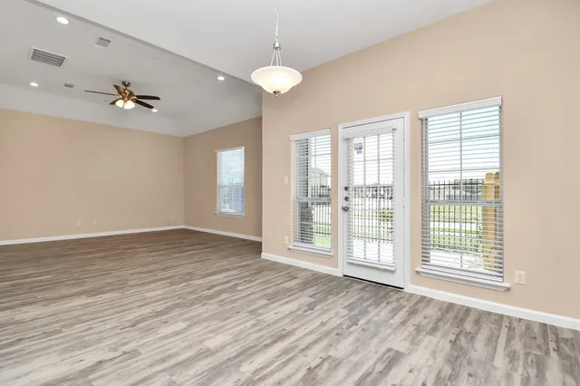 a view of an empty room with a window and wooden floor