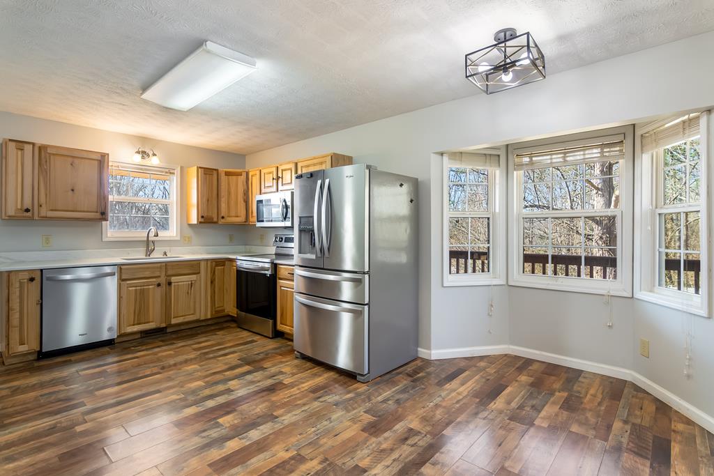 65 Ivy Ridge Ellijay, GA 30536 - Photo 11 of 28 a kitchen with granite countertop a refrigerator cabinets stainless steel appliances and a window