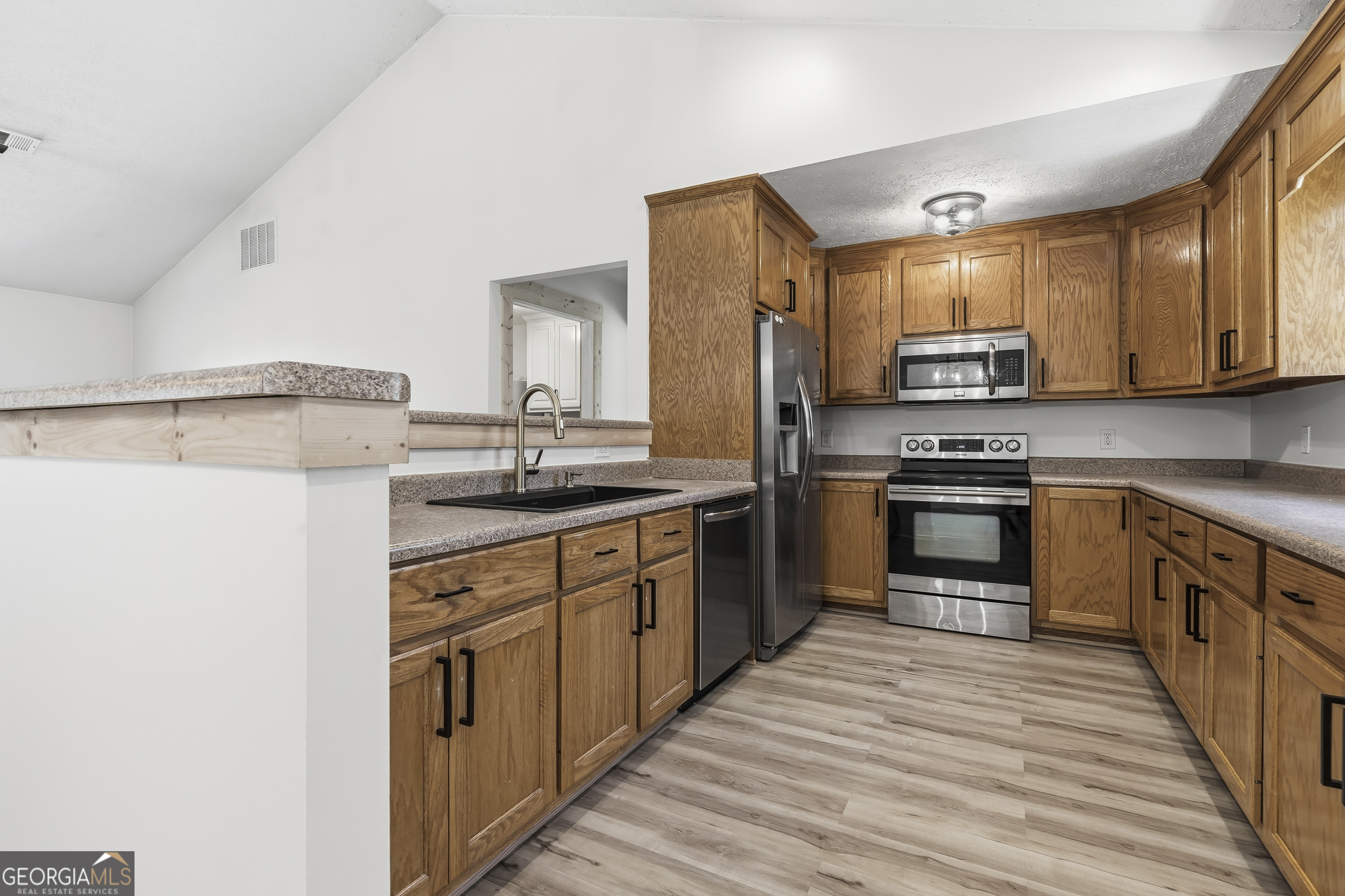 176 Arrowhead Trail Eatonton, GA 31024 - Photo 14 of 45 a kitchen with stainless steel appliances granite countertop a stove top oven a sink and a refrigerator
