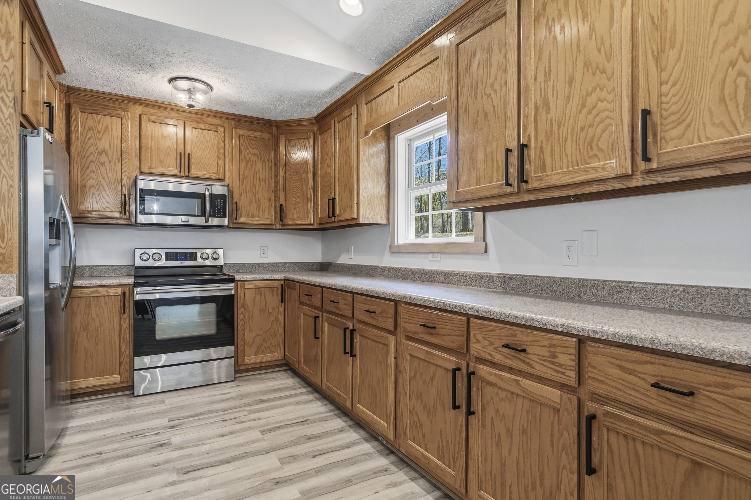 176 Arrowhead Trail Eatonton, GA 31024 - Photo 16 of 45 a kitchen with stainless steel appliances granite countertop a stove a sink and a microwave