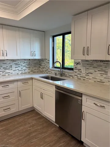 a kitchen with granite countertop white cabinets sink and window