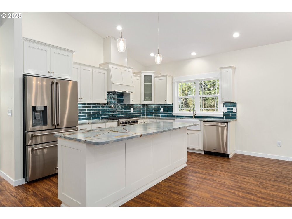 1241 Lighthouse Lane Brookings, OR 97415 - Photo 13 of 32 a kitchen with stainless steel appliances granite countertop a refrigerator a sink dishwasher a stove and white countertops with wooden floor