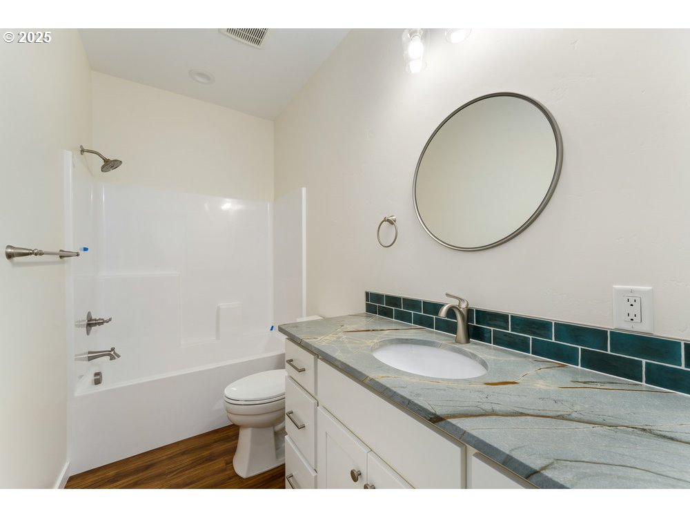 1241 Lighthouse Lane Brookings, OR 97415 - Photo 9 of 32 a bathroom with a granite countertop toilet a sink and a mirror