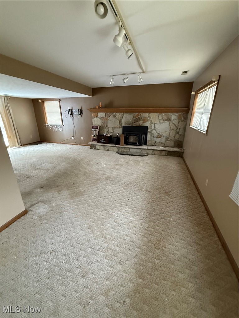 8335 Shepard Road Macedonia, OH 44056 - Photo 8 of 17 Unfurnished living room with track lighting, a wood stove, plenty of natural light, and carpet floors