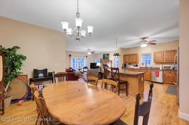 a large kitchen with stainless steel appliances a stove a refrigerator a sink dishwasher a dining table and chairs with the wooden floor