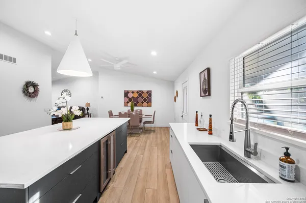 a kitchen with stainless steel appliances a sink dishwasher stove and white cabinets next to a window