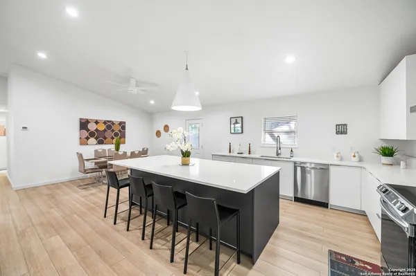 a kitchen with stainless steel appliances kitchen island a table chairs in it and wooden floors