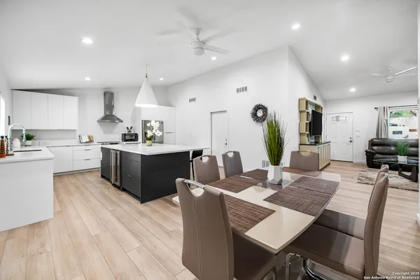 a kitchen with a dining table chairs and wooden floor