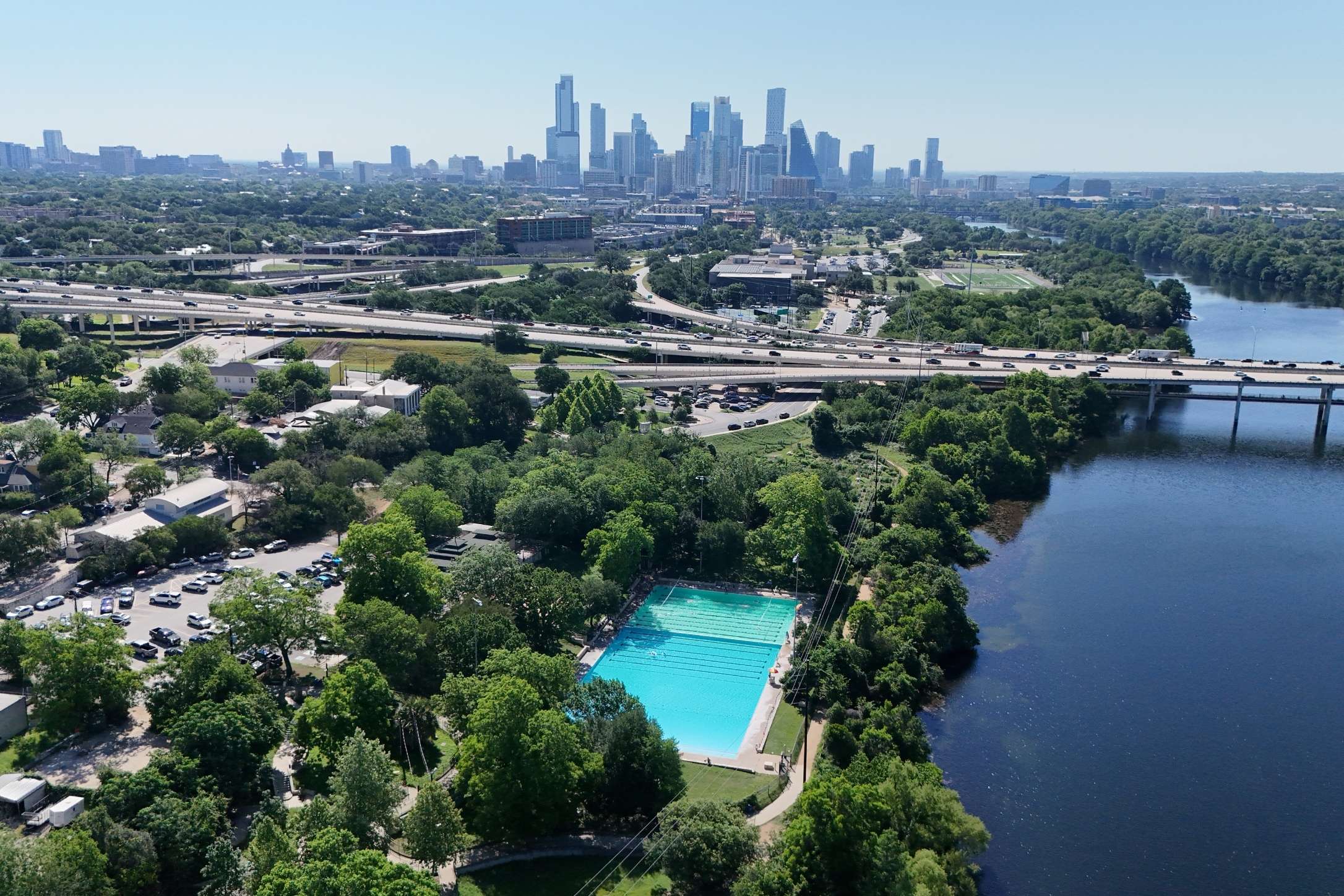 2208 Enfield Road, Unit 10500 Austin, TX 78703 - Photo 13 of 34 Aerial perspective highlighting a large outdoor swimming pool bordered by mature trees and a substantial body of water