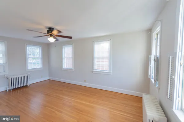 an empty room with wooden floor fan and windows