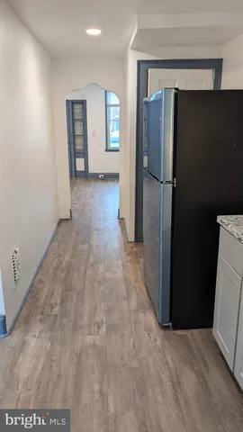 a view of a refrigerator in kitchen and an empty room with windows