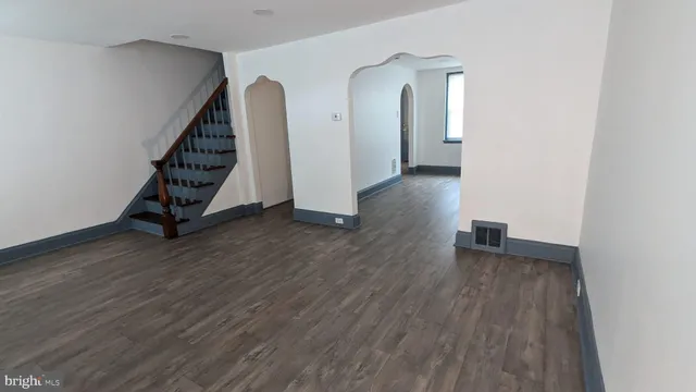 an empty room with wooden floor and stairs
