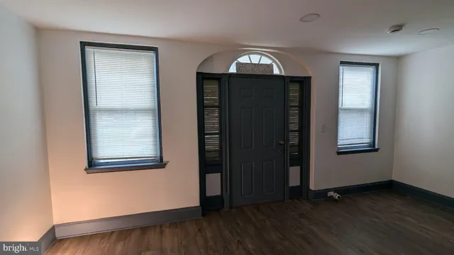 an empty room with wooden floor closet and windows