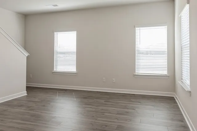 an empty room with wooden floor and windows