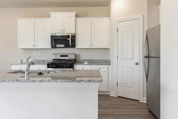 a kitchen with stainless steel appliances granite countertop a refrigerator a sink a stove a microwave and cabinets
