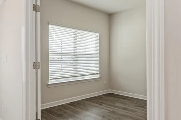 a view of an empty room with wooden floor and a window
