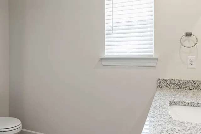 a bathroom with a granite countertop window and a toilet