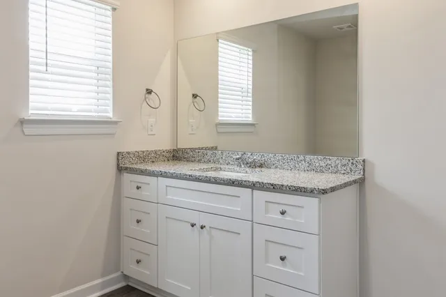 a bathroom with a granite countertop sink and a mirror