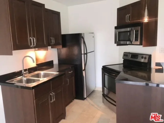 a kitchen with granite countertop a sink stove and refrigerator